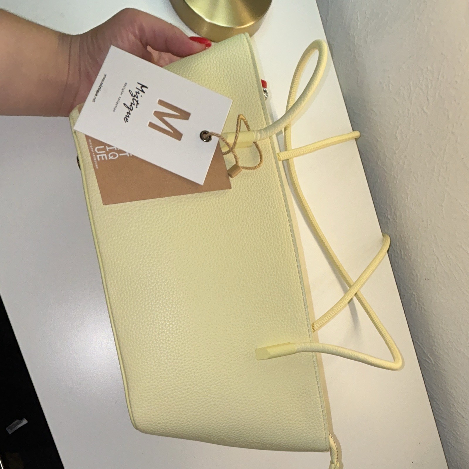 Brand new purse with original tag attached. Cute light yellow/cream tote bag.