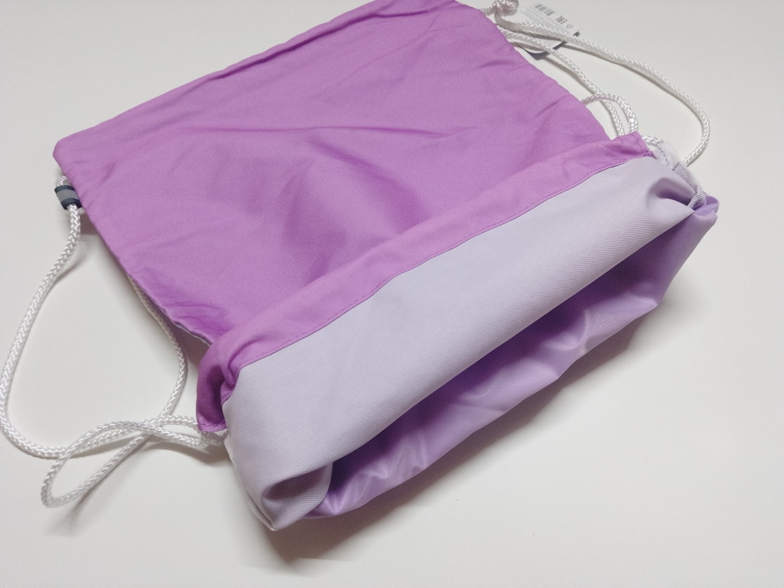 a purple quilted drawstring bag with an iridescent design and white drawstring