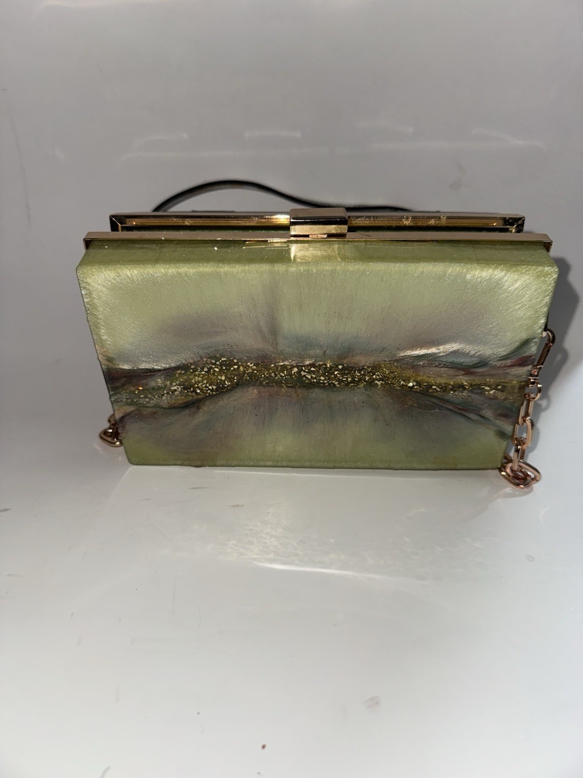 marbled acrylic box clutch bag with a gold clasp and strap