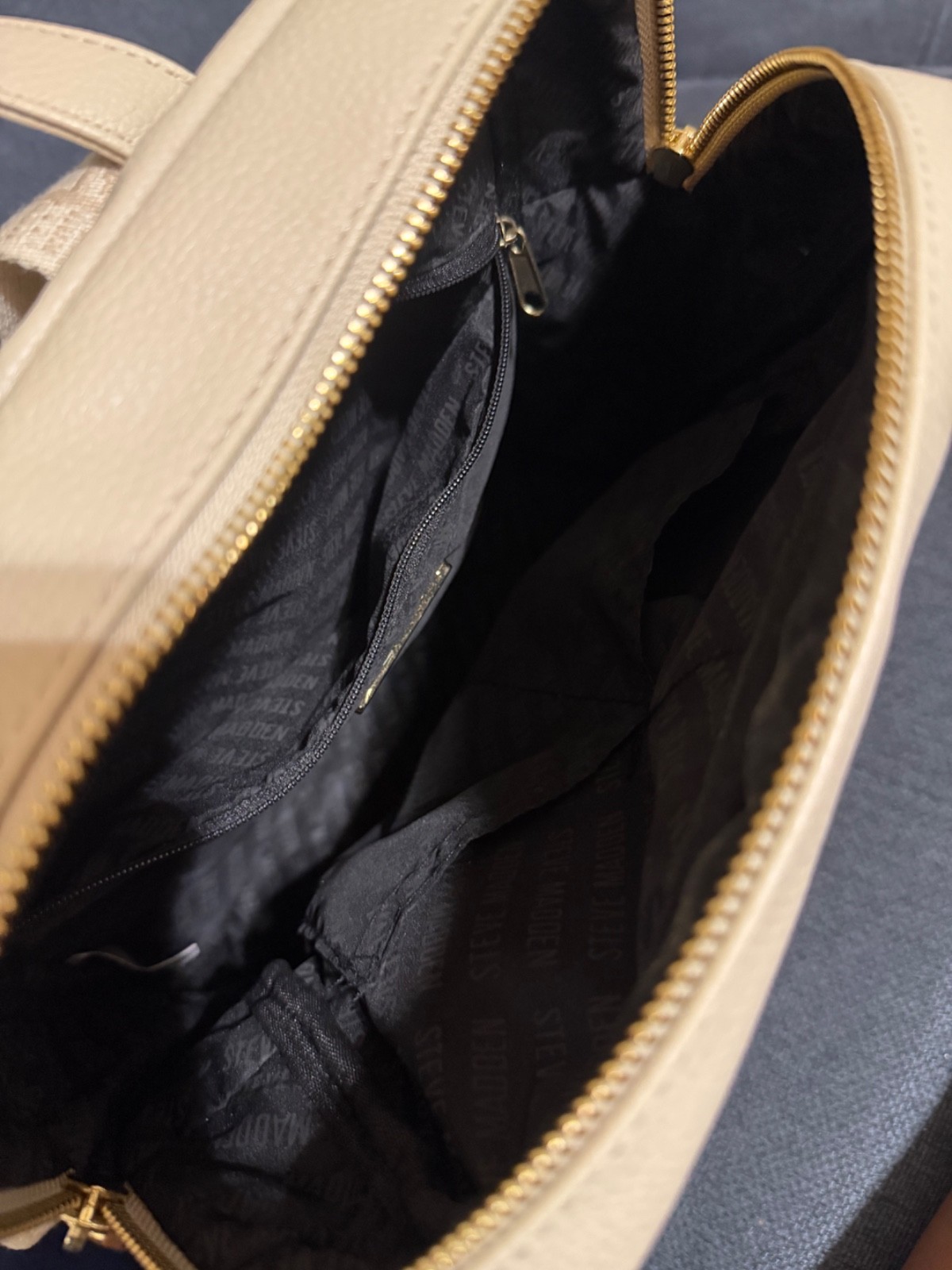 Steve Madden cream & tan backpack with repeating ‘STEVE MADDEN’ text in a grid p