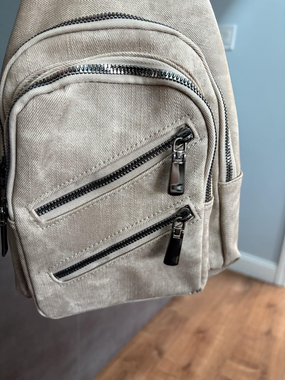 beige washed canvas sling bag embroidered strap multiple zippered pockets.