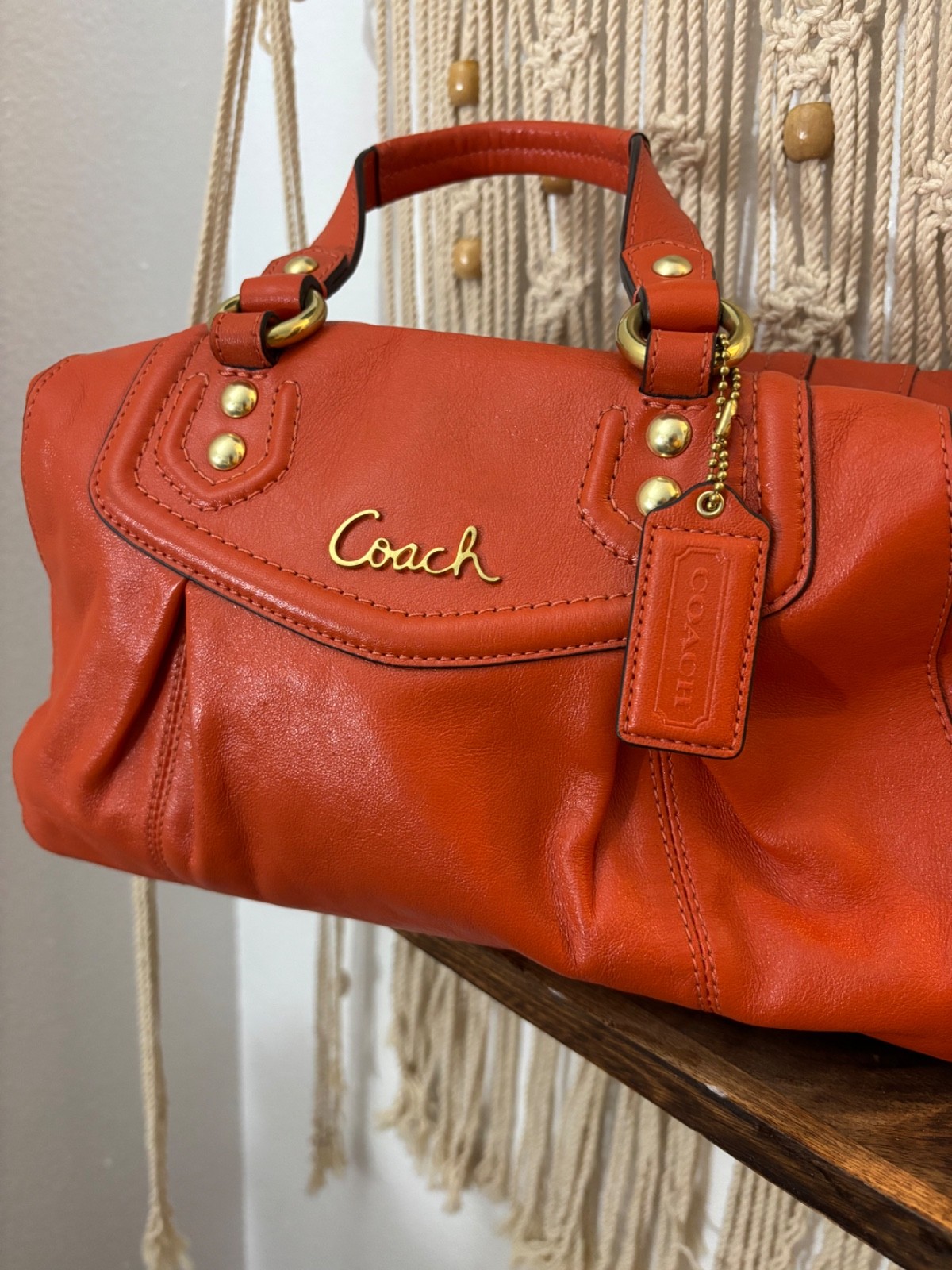 orange leather Coach Ashley satchel features gold-tone hardware and a silver-lin