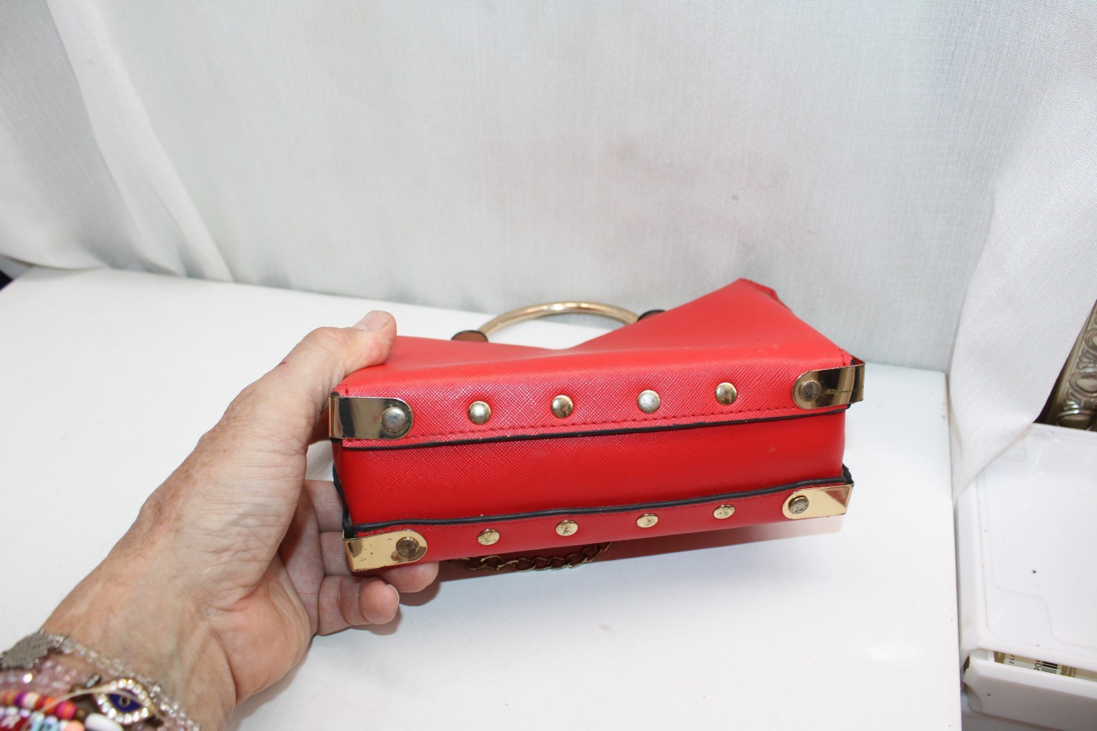 structured red vinyl handbag with a gold-toned chain strap and a top handle.
